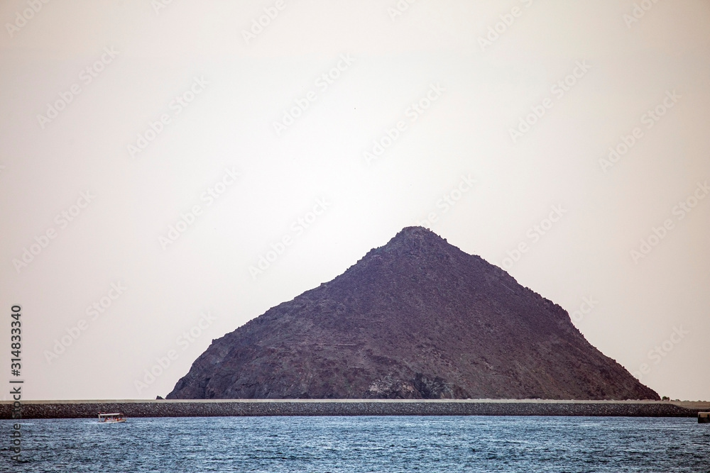mountain in the middle of the sea against the sky