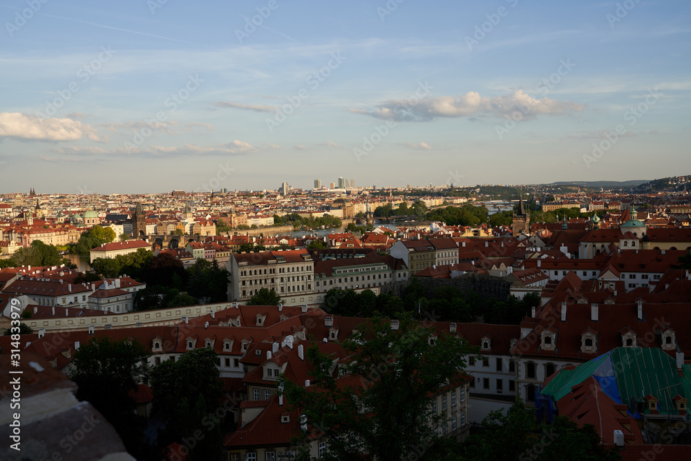 Typical roofs. Top view - roofs with red tiles in old buildings. There are beautiful houses in green trees. Horizontal photo colorful European city Prague in Czech Republic, travel in tourist place Typical roofs. Top view - roofs with red tiles in old buildings. There are beautiful houses in green trees. Horizontal photo colorful European city Prague in Czech Republic, travel in tourist place