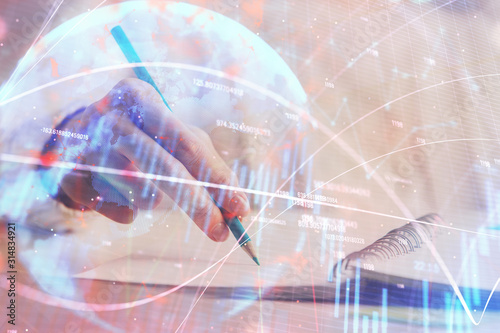 Financial forex graph displayed on hands taking notes background. Concept of research. Double exposure