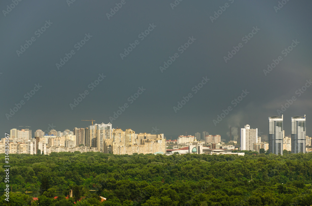 View of modern residential area against the background of gray cloudy sky after rain and lush foliage in summer. Left bank of Kyiv, Ukraine. Copy space