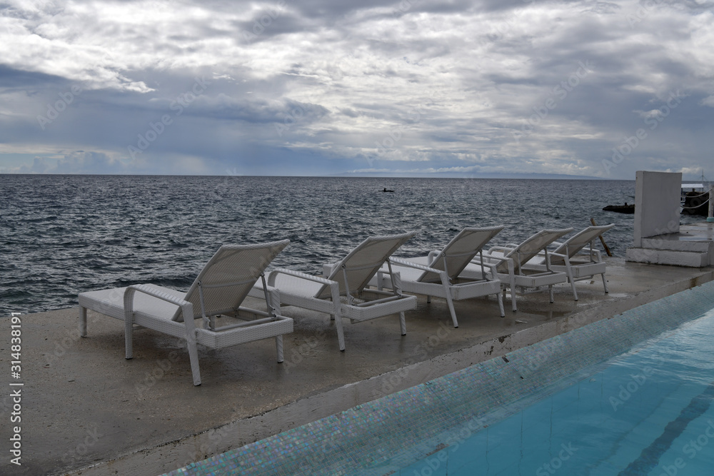 Fototapeta premium sea view before the rain with white sunbeds for sunbathing