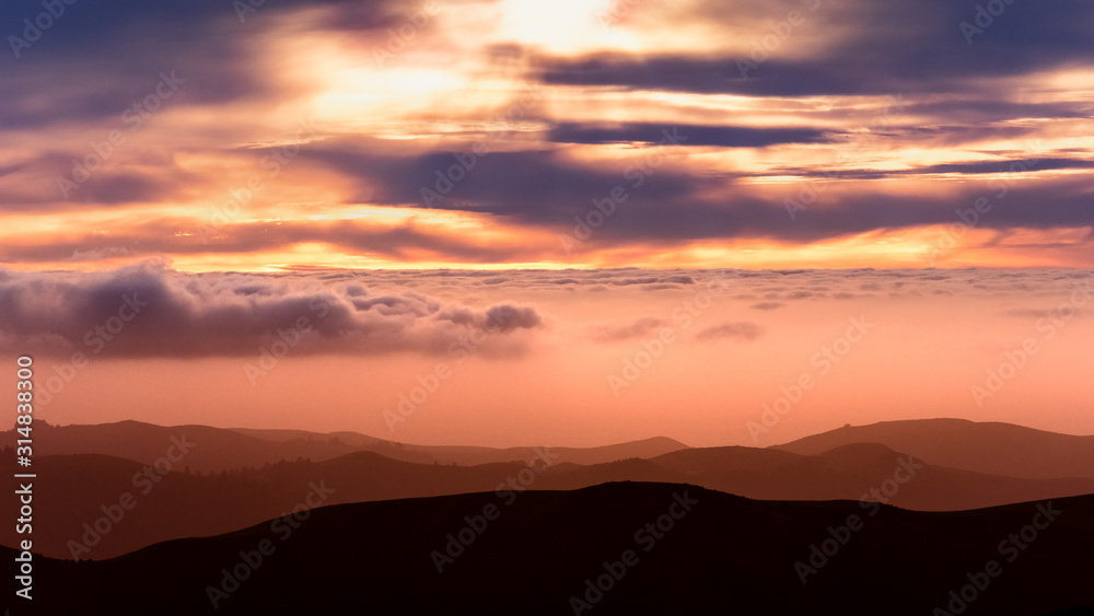 Sunset view of sea of clouds covering the hills and valleys of Santa Cruz mountains; San Francisco bay area, California