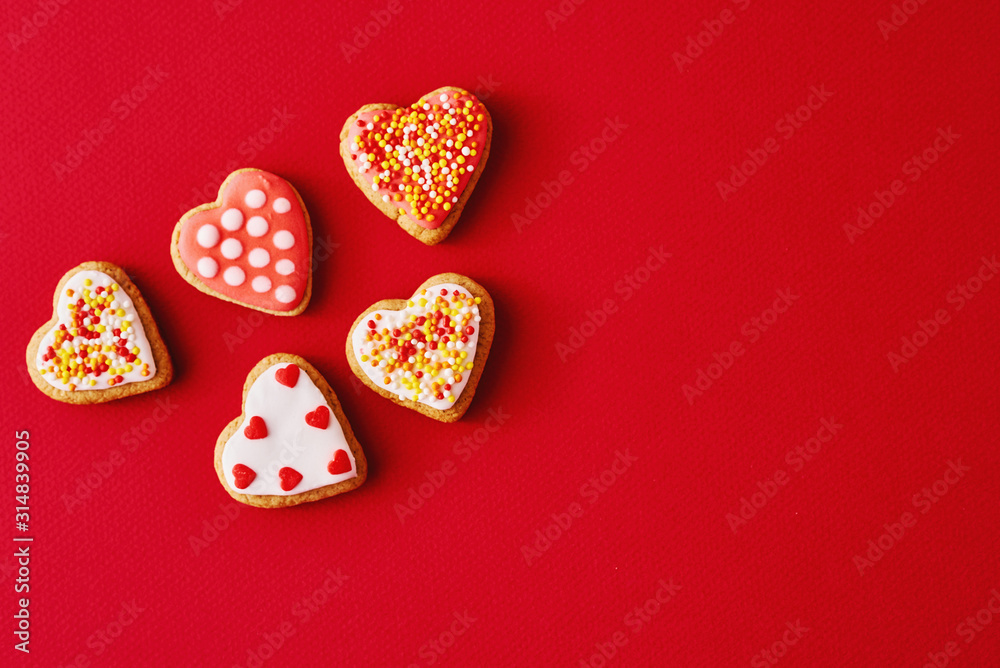 Decorated with icing and glazed heart shape cookies on the red background with copy space. Valentines Day food concept Decorated with icing and glazed heart shape cookies on the red background with copy space. Valentines Day food concept