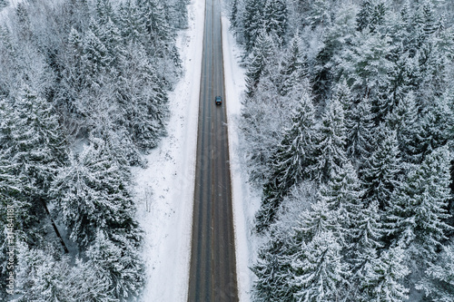 Aerial view of winter road with a car and snow covered forest in Finland © nblxer