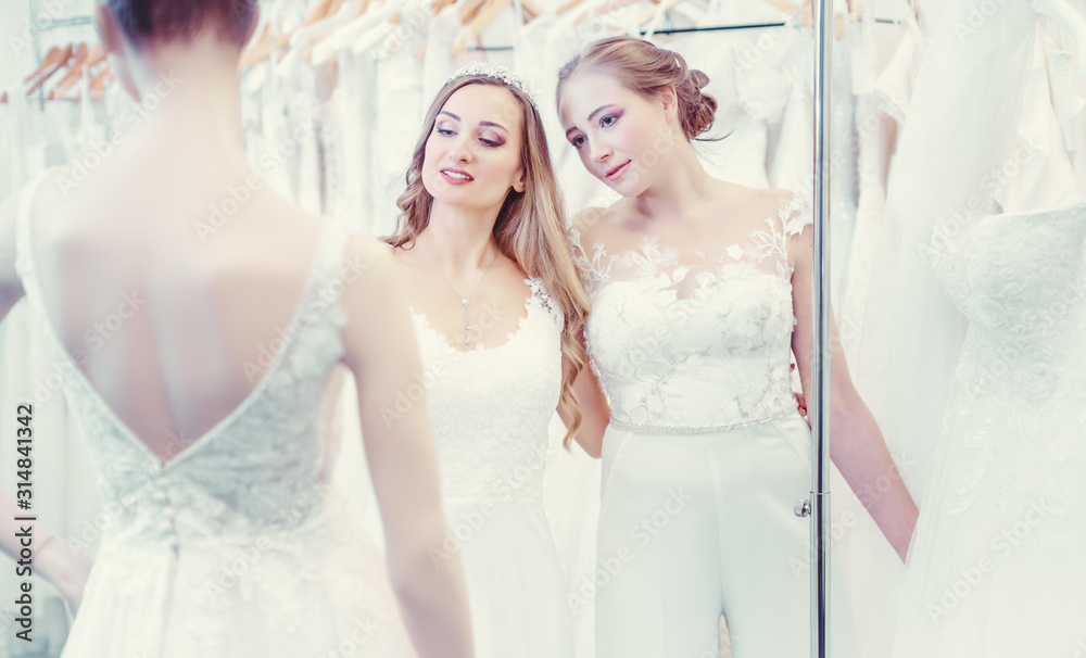 Two brides same sex wedding couple looking at dress mannequin Two brides same sex wedding couple looking at dress mannequin