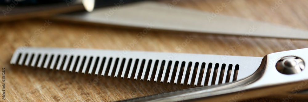 Metallic Scissors of Hairdresser Closeup Photo. Cutting Tools for Barbershop on Wooden Background. Metallic Instrument with Comb for Hair Styling. Stainless Accessory Partial View Photography Metallic Scissors of Hairdresser Closeup Photo. Cutting Tools for Barbershop on Wooden Background. Metallic Instrument with Comb for Hair Styling. Stainless Accessory Partial View Photography