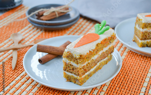 Carrot Cake Day.  National holiday. Carrot cake with cream cheese frosting decorated with chocolate carrots on an orange background, stylized table setting.  Close-up, top view .