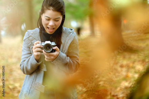closeup asian woman hand use cemera gear traveller with background of autumn garden falling season,asian photograper travel with happiness and joyful moment with camera vacation concept photo