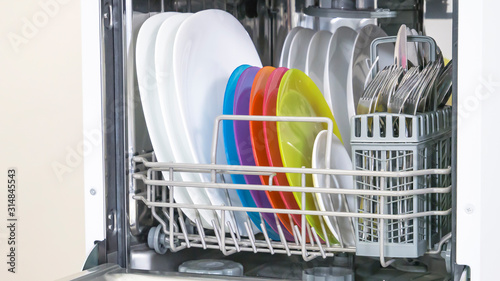 colorful Dishware inside built-in dishwasher. Dishwashing machine rack