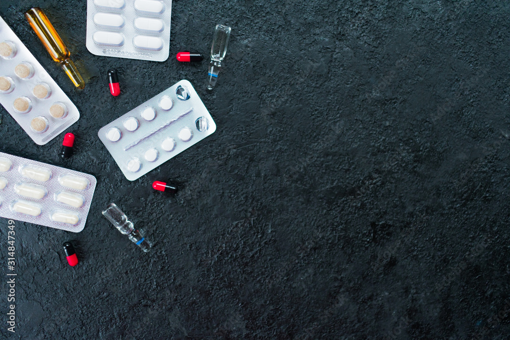 Ampoules for injections, pills and capsules on a black background. Copy space. Ampoules for injections, pills and capsules on a black background. Copy space.