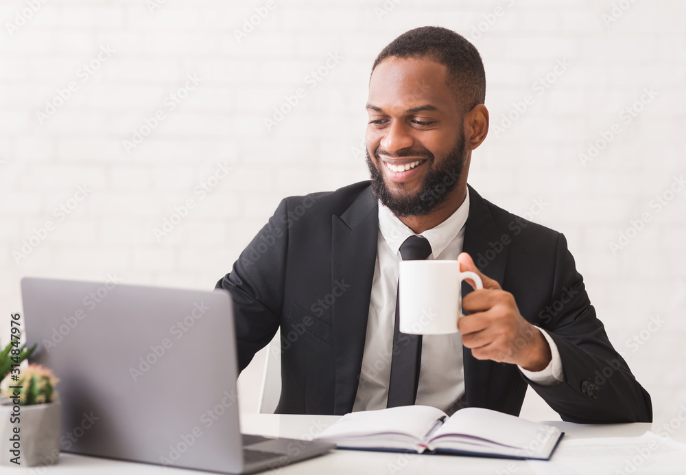 Inspired young entrepreneur drinking tea while working in office Inspired young entrepreneur drinking tea while working in office