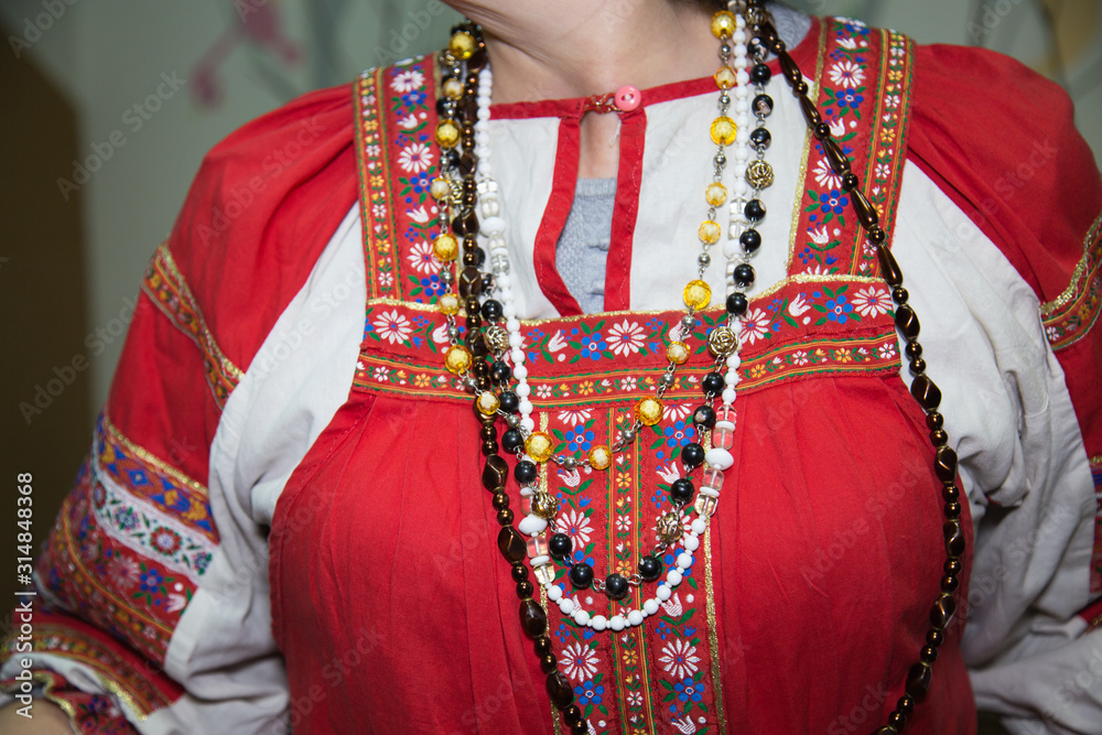 Traditional folk ornaments on a red sundress of a woman decorated with a beautiful national ornament. Clothing, jewelry, traditions.