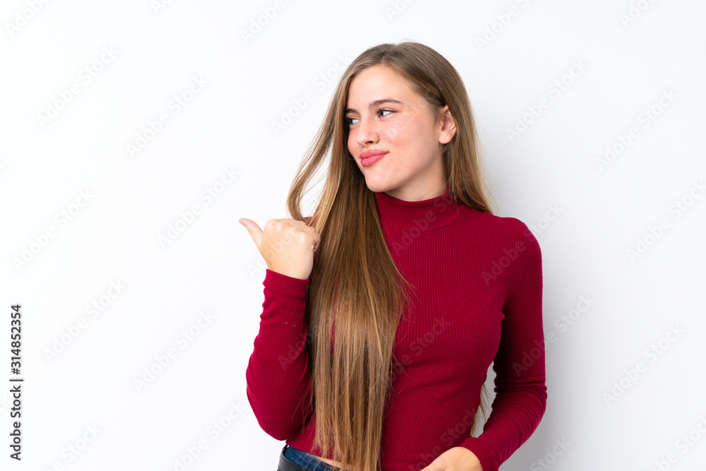Teenager blonde girl over isolated white background pointing to the side to present a product Teenager blonde girl over isolated white background pointing to the side to present a product