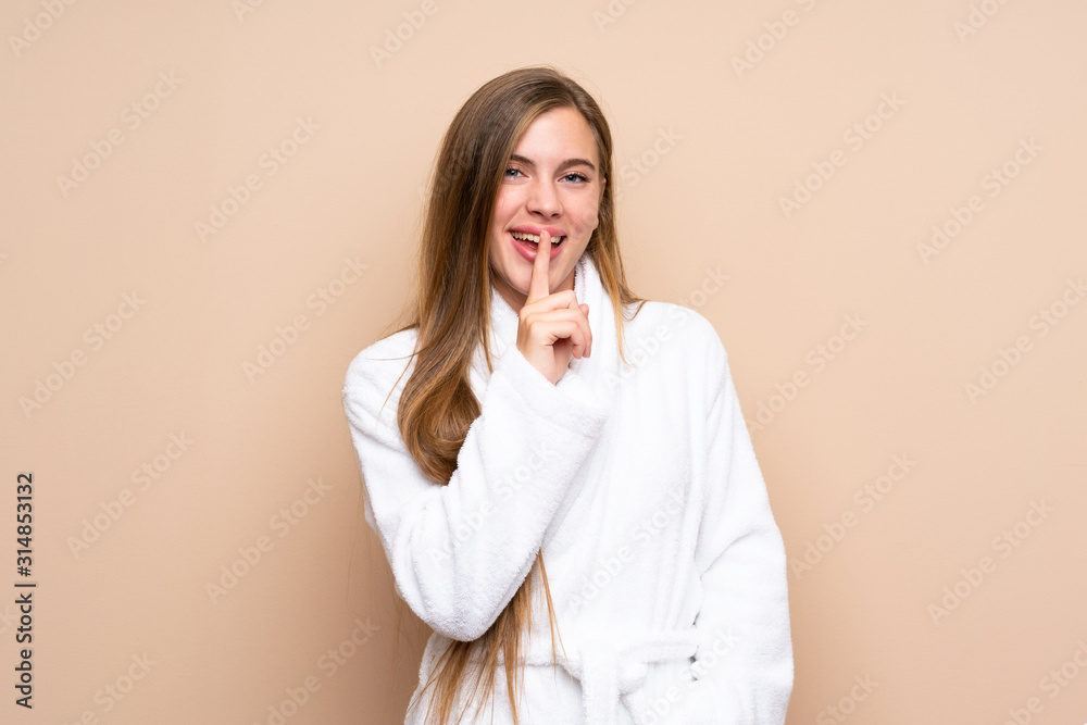 Teenager girl in a bathrobe over isolated background doing silence gesture Teenager girl in a bathrobe over isolated background doing silence gesture