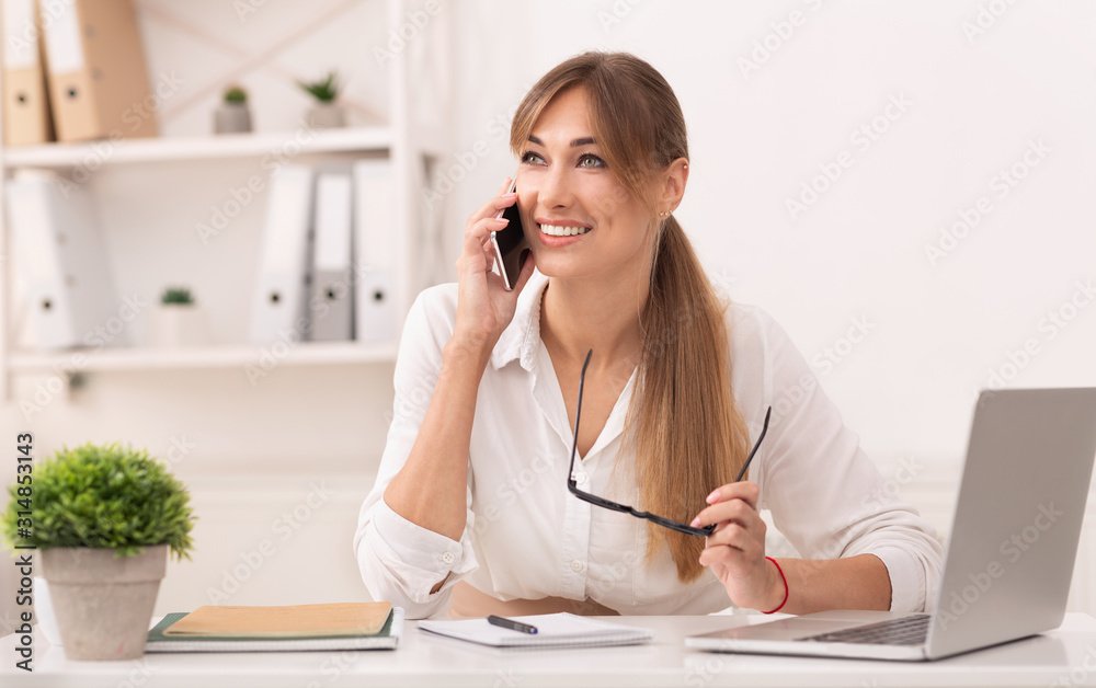 Joyful Entrepreneur Talking On Cellphone Sitting At Laptop In Office Joyful Entrepreneur Talking On Cellphone Sitting At Laptop In Office