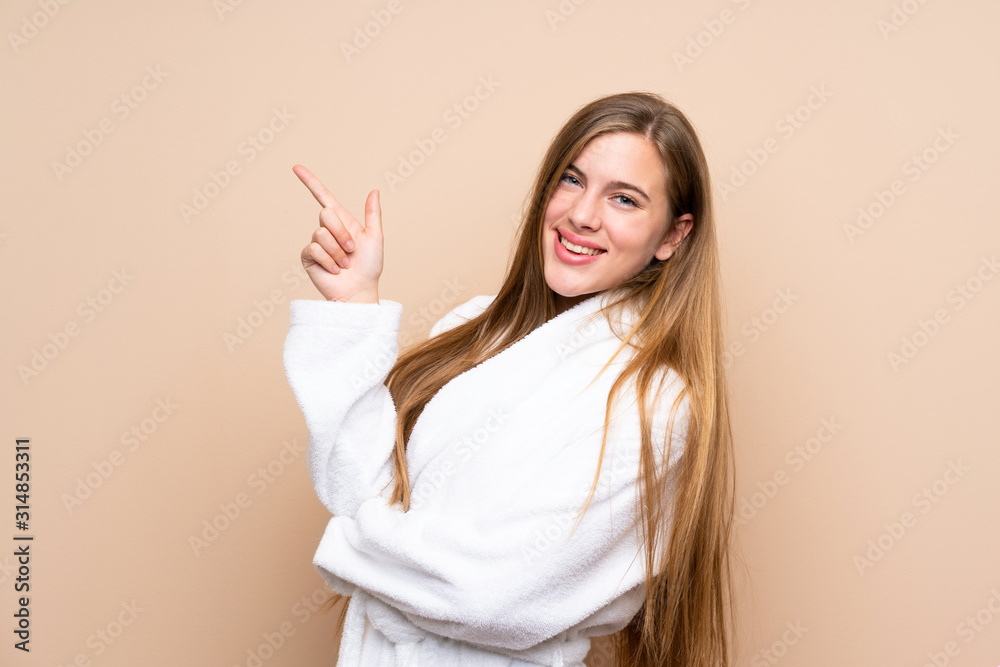 Teenager girl in a bathrobe over isolated background pointing finger to the side Teenager girl in a bathrobe over isolated background pointing finger to the side