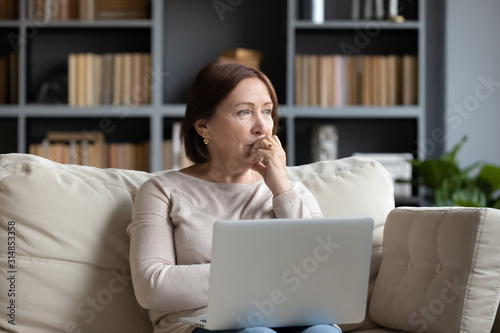 Pensive middle-aged woman look in distance pondering photo
