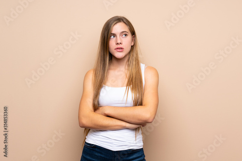 Teenager blonde girl over isolated background with confuse face expression