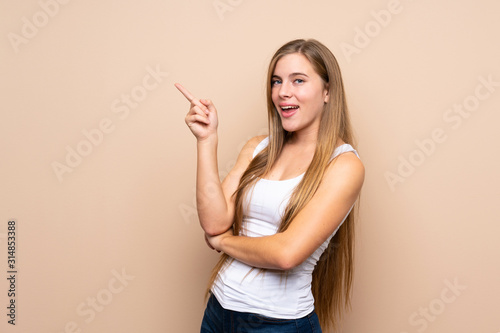 Teenager blonde girl over isolated background pointing finger to the side