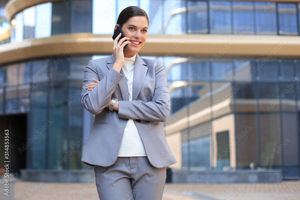 Portrait of stylish smiling business woman in fashionable clothes calling on mobile phone near office. Portrait of stylish smiling business woman in fashionable clothes calling on mobile phone near office.