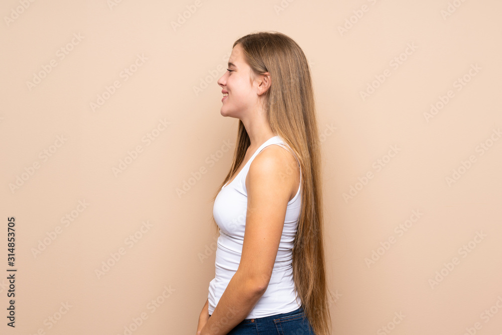Teenager blonde girl over isolated background in lateral position Teenager blonde girl over isolated background in lateral position