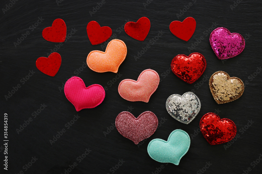Fototapeta premium Valentines day concept. red glitter hearts over black background. Flat lay composition