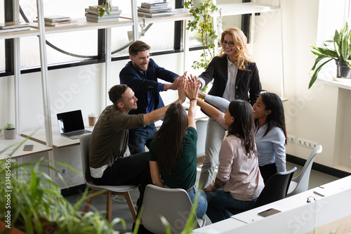 фотографія Diverse office staff giving high five celebrating success showing unity