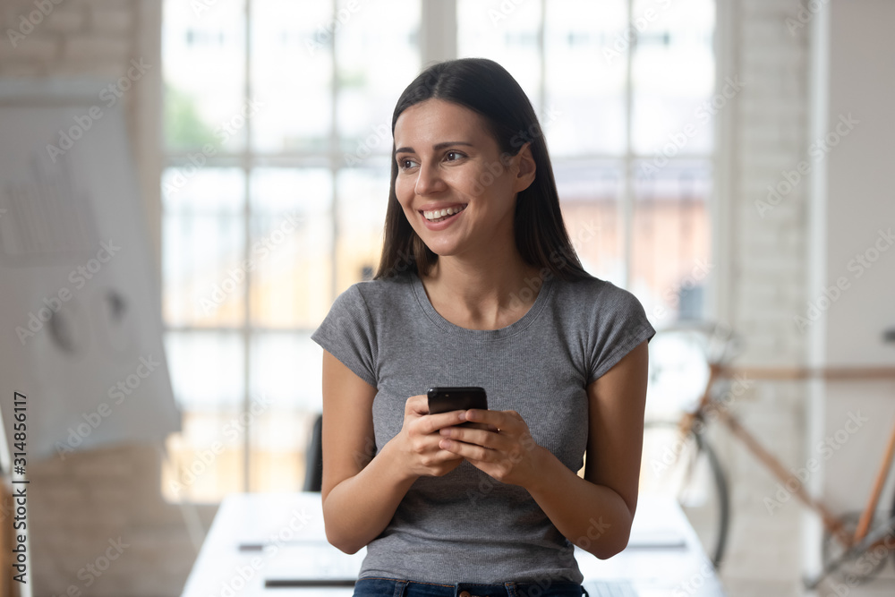 Happy Caucasian female with smartphone in hands dreaming Happy Caucasian female with smartphone in hands dreaming