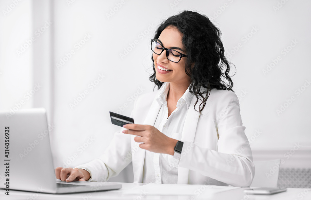 Smiling latin woman making purchases using computer Smiling latin woman making purchases using computer