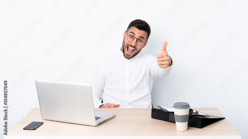 Young businessman in a workplace with thumbs up because something good has happened Young businessman in a workplace with thumbs up because something good has happened