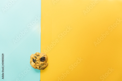 Cookies that contain a mixture of almonds and raisins. Placed on a yellow and blue background with copy space.pastle style