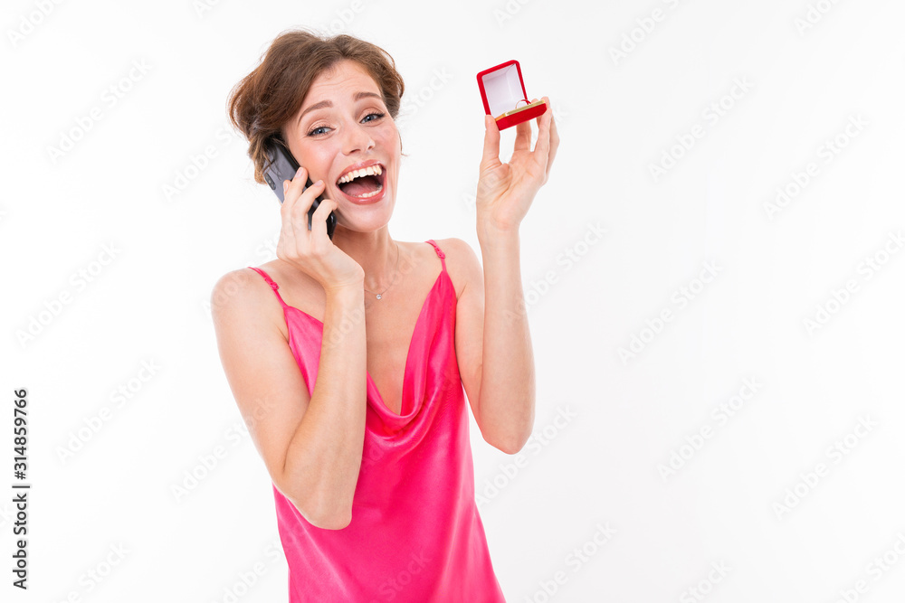 portrait of a cute happy surprised caucasian girl with a box with a ring in her hands calls on a telon and reports joy on a white background portrait of a cute happy surprised caucasian girl with a box with a ring in her hands calls on a telon and reports joy on a white background