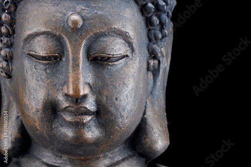 Porträt des Kopfes einer Buddha-Figur aus Bronze freigestellt auf schwarzem Hintergrund mit Platz für Text