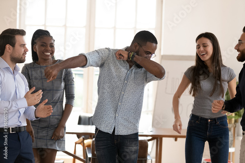 Happy diverse employees have fun dancing in office