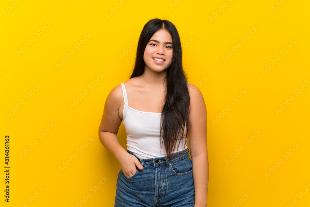 Young teenager Asian girl over isolated yellow background laughing Young teenager Asian girl over isolated yellow background laughing