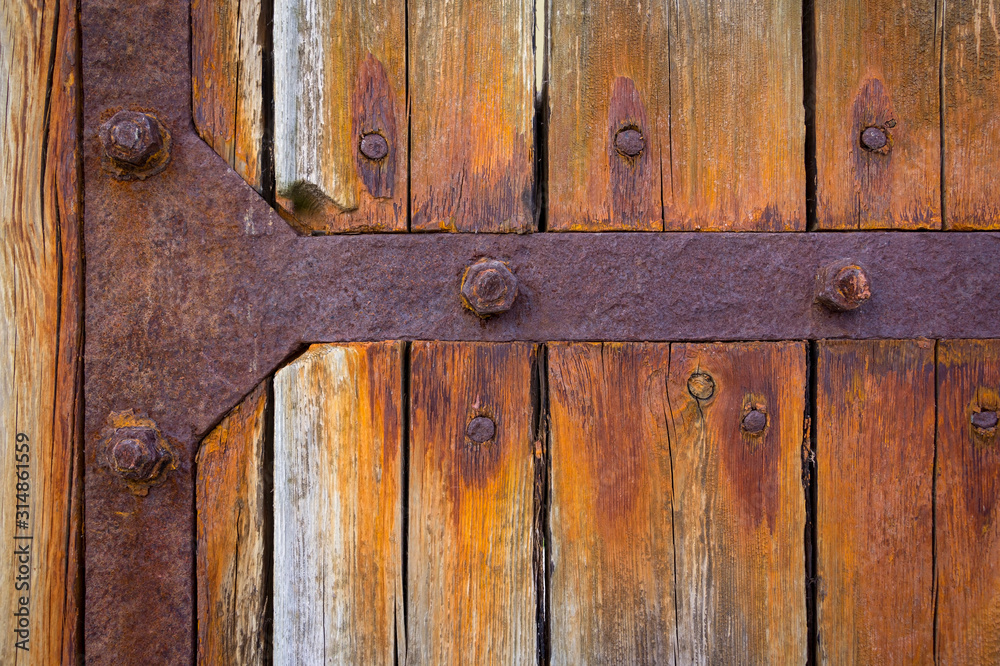 Detail of a large wooden gate with rusted iron fittings. Detail of a large wooden gate with rusted iron fittings.
