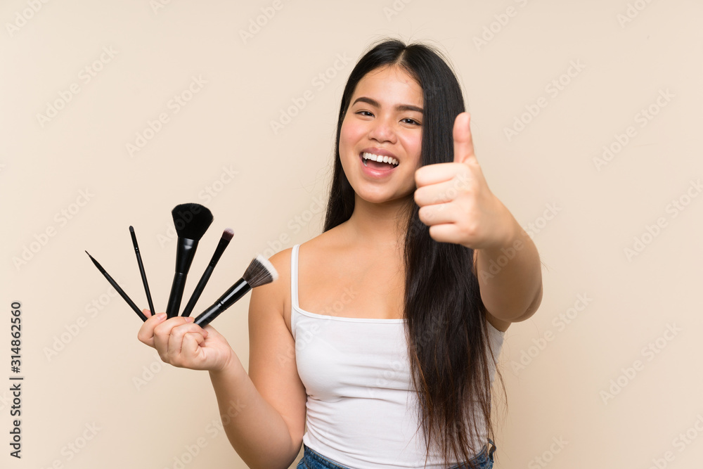 Young teenager Asian girl holding a lot of makeup brush with thumbs up because something good has happened Young teenager Asian girl holding a lot of makeup brush with thumbs up because something good has happened