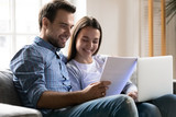 Young couple sit on couch paying bills online