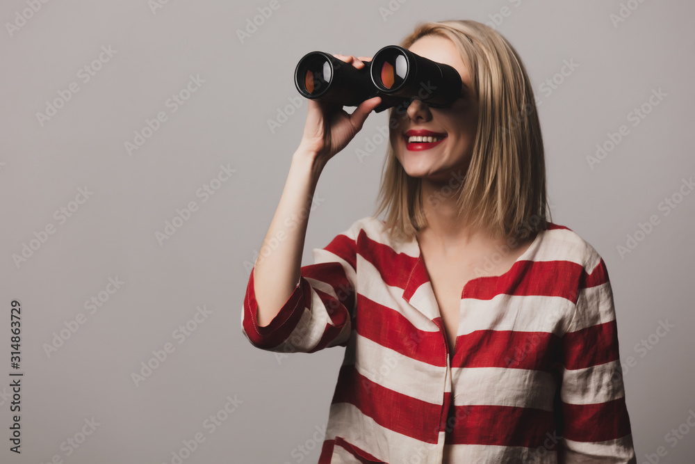 beatiful girl in jacket holds binoculars on grey back beatiful girl in jacket holds binoculars on grey back