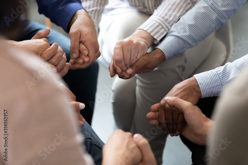 People sitting in circle holding hands at group therapy session