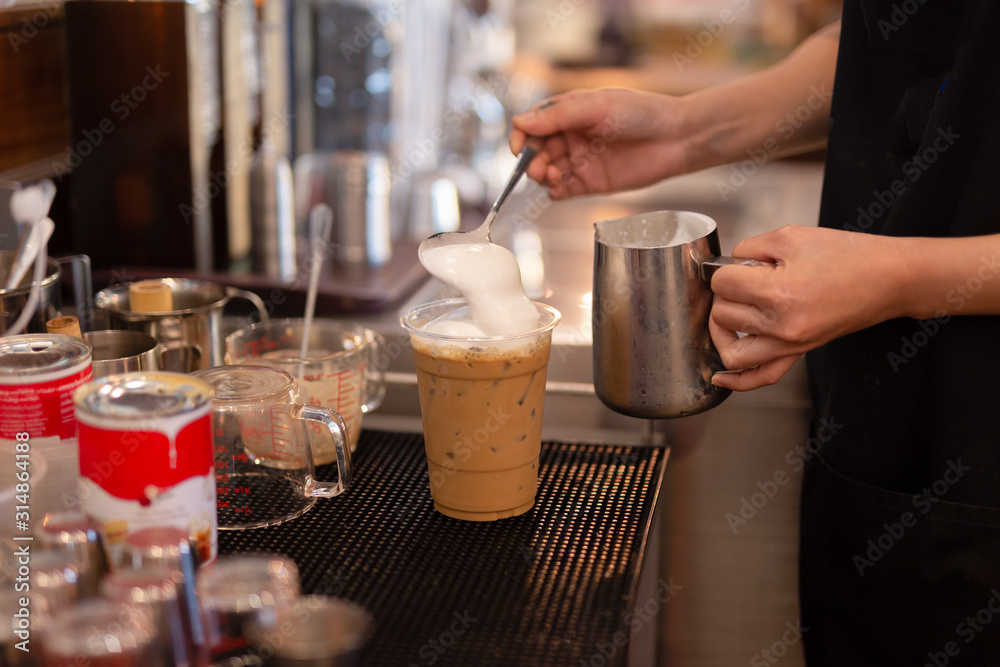 Barista hand topped whipping cream on the top of ice Coffee.