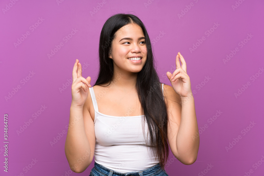 Young teenager Asian girl over isolated purple background with fingers crossing Young teenager Asian girl over isolated purple background with fingers crossing