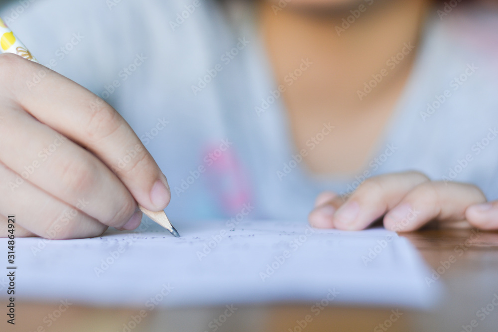 Close up kid's hand writing on paper, writing messy math on wooden table in room,student child girl holding pen doing homework at home, calculate the results on paper , education concept Close up kid's hand writing on paper, writing messy math on wooden table in room,student child girl holding pen doing homework at home, calculate the results on paper , education concept