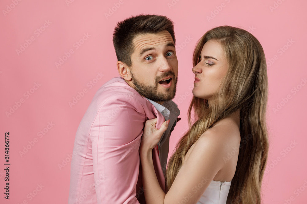 angry woman shouting at her boyfriend on pink background. couple arguing