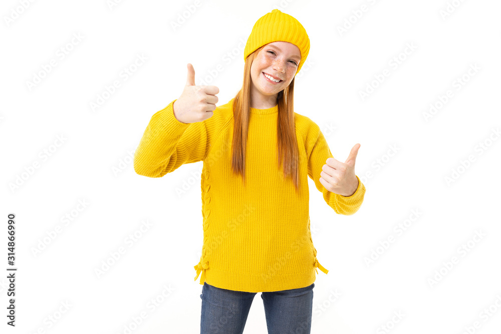 Happy teenager girl with red hair, yellow hoody and trousers shows like isolated on white background Happy teenager girl with red hair, yellow hoody and trousers shows like isolated on white background