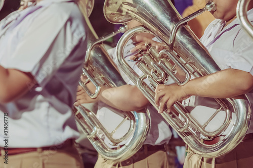 Obraz na plátně Male student with friends blow the euphonium with the band for performance on stage at night