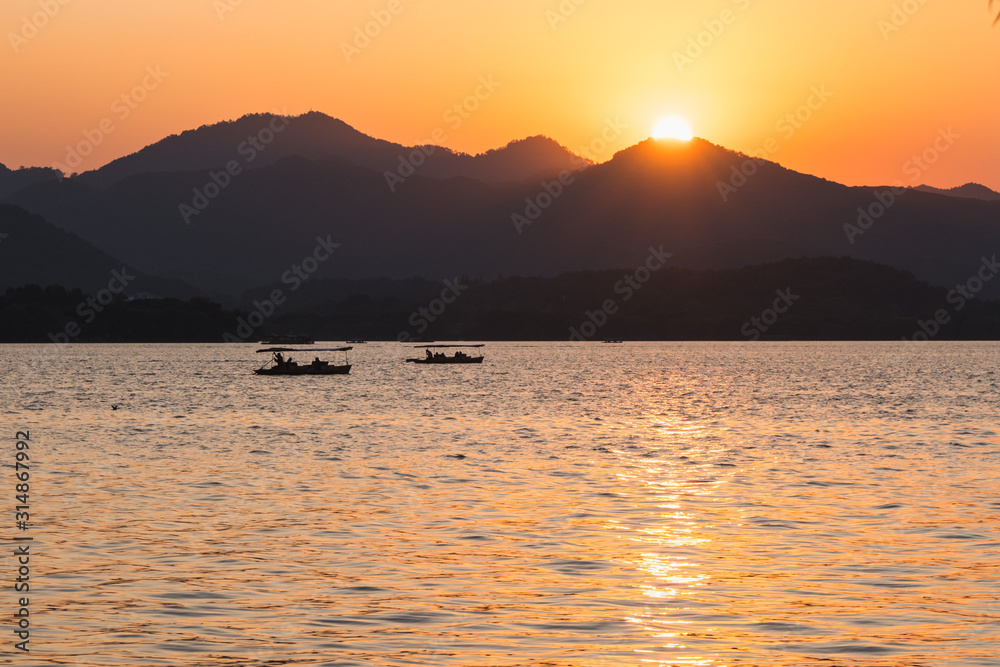 Sunset panoramic view of the West Lake in Hangzhou, China. Beautiful silhouettes in sunset colors.