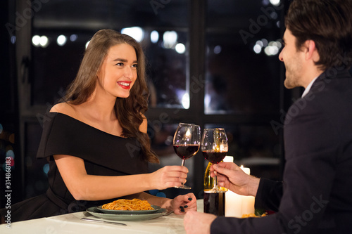 Happy couple in love clinking with wine Valentine date