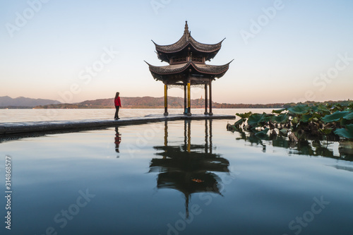 Sunrise panoramic view of the West Lake in Hangzhou, China. Girl silhouette in sunrise colors.