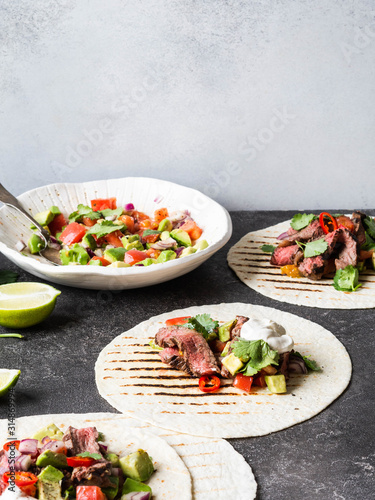 Tortillas with vegetables and beef steak slices. Avocados, tomatoes, red onions and meet with cilantro and lime juice in tortillas. Mexican food.